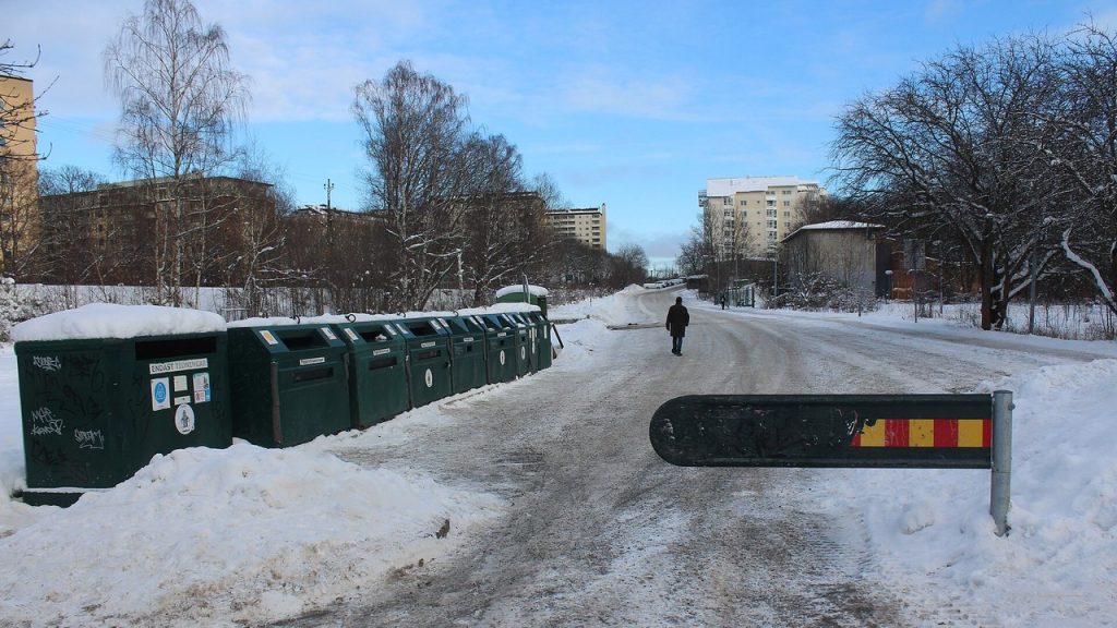 Gröna återvinningskärl för förpackningar vid en återvinningsstation i Huvudsta, Solna, en snöig vinterdag