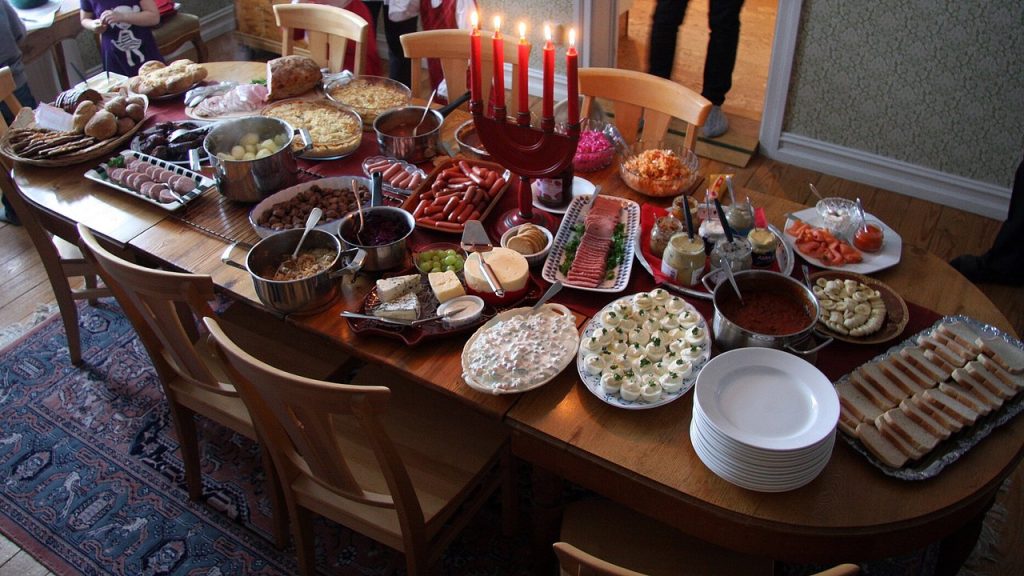 Dukat julbord med ägghalvor, korv, varma rätter och adventsljusstake i ett svenskt hem