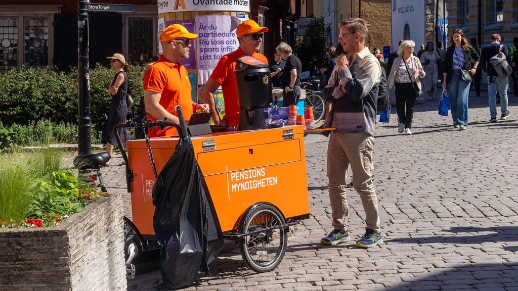 Pensionsmyndighetens orangea lastcykel och personal som informerar besökare på en gata i Visby